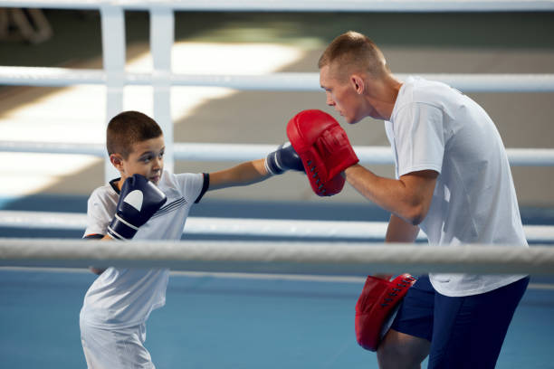 istock School age boy, beginner boxer practicing punches with personal coach at sports gym, indoors. Concept of studying, challenges, sport, hobbies, competition 1433091416
