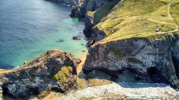 aerial shot of the carrick-a-rede (national trust) rope bridge with a sea connecting two cliffs - national trust northern ireland uk rock imagens e fotografias de stock