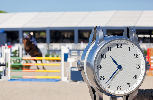 An equestrian show jumper in an arena competes for a fast time against the clock