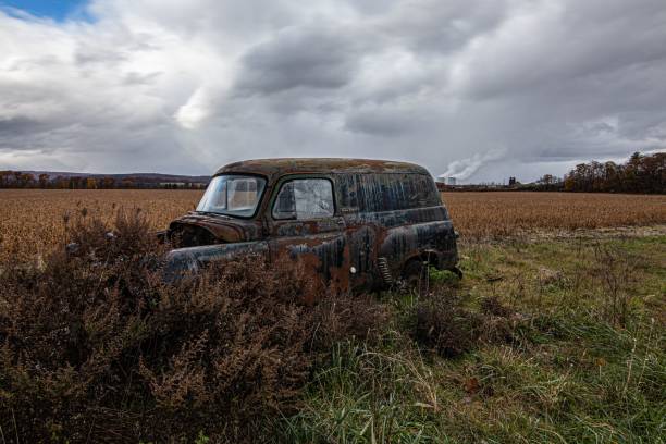 istock Old rusty car abandoned in the green and brown field under cloudy sky 1433094517