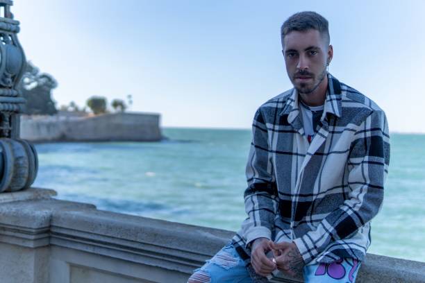 A handsome caucasian man sitting on a bridge.