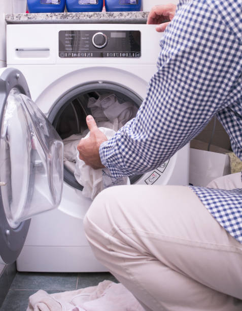istock Mature Man Loading clothes and linen in washing machine. Doing laundry at home 1433098879