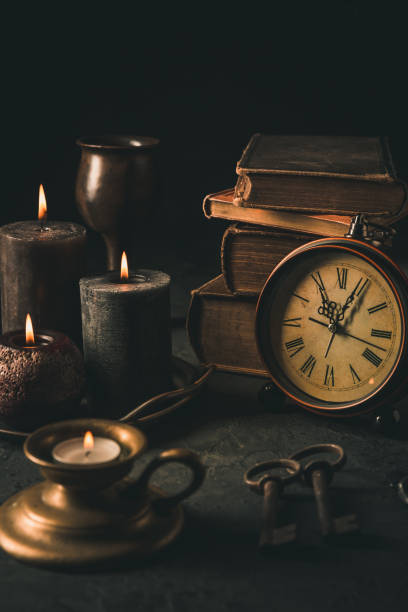 Candles,  antique books, old clock and old rusty keys in vintage style on black background