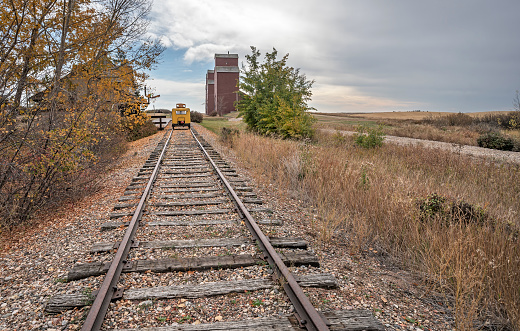 Train tracks with a speeder leading to the village of Rowley, Alberta and its grain elevators