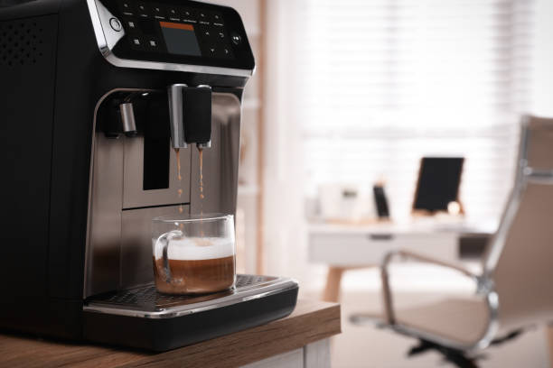istock Modern espresso machine pouring coffee into cup in office. Space for text 1433104141