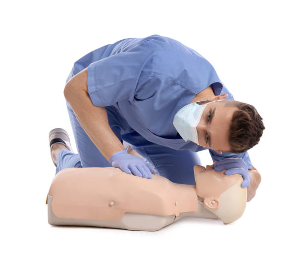 istock Doctor in uniform and protective mask practicing first aid on mannequin against white background 1433104828