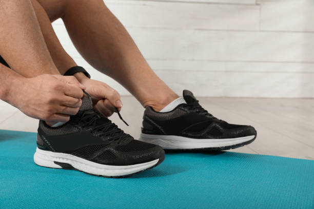 istock Man tying sneaker's shoelaces on exercise mat indoors, closeup 1433105821