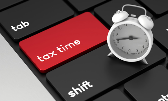 Close-Up Laptop Keyboard With Tax Time Button and Alarm Clock. Time and Deadline Concept.