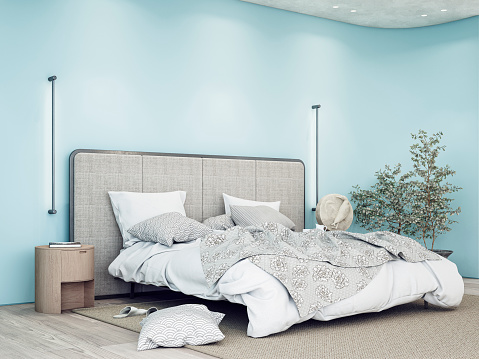 Luxury bedroom with a gray textile headboard bed, white and gray sheets - bedding,  night tables, a sculpture, pillows, a beige carpet, and vertical wall lights on the hardwood floor. A large eucalyptus plant in a pot in front of a rounded light blue empty plaster wall with copy space and built-in reflector lights on the ceiling. 3D rendered image.