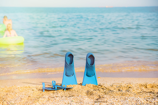 flippers on a sandy beach, blue sky and sea in the background, traveland holiday time