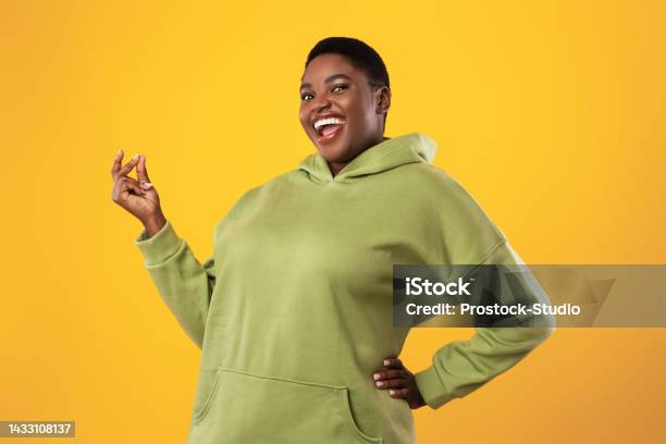 Joyful Overweight Black Woman Snapping Fingers Over Standing Yellow Background Stock Photo - Download Image Now