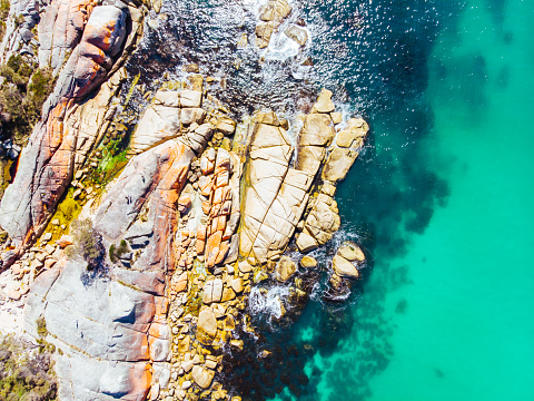 The iconic lichen covered rocks and turqoise ocean water in the Bay of Fires taken as an aerial image near Binalong Bay, Tasmania, Australia