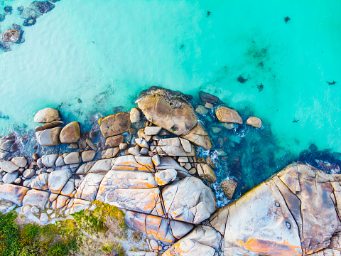 The iconic lichen covered rocks and turqoise ocean water in the Bay of Fires taken as an aerial image near The Gardens in Tasmania, Australia