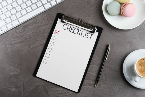 istock Clipboard with inscription Checklist, cup of coffee, computer keyboard and macarons on grey table, flat lay 1433113344