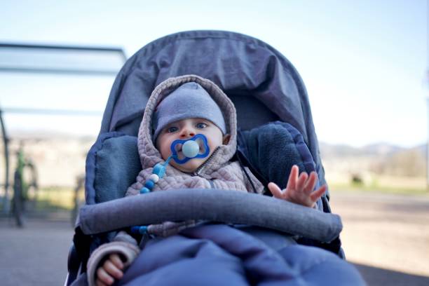 istock Cute baby boy sitting in stroller outside and rising left hand 1433114618