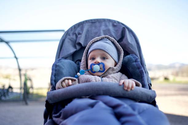 Baby boy sitting in a baby stroller outdoors Adorable baby boy sitting inside his pram outdoors baby stroller winter stock pictures, royalty-free photos & images