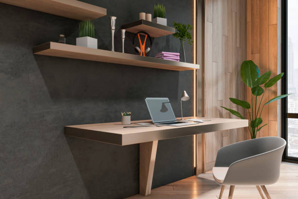 istock Perspective view on stylish work place table with modern laptop in sunlit cabinet with dark and wooden wall and grey chair. 3D rendering 1433114954