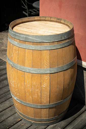 An oak barrel stands on the outdoor near the wall.