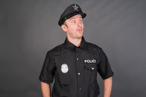 Portrait of Caucasian man wearing police uniform costume against gray studio background