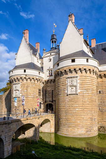 Nantes, France - September 16, 2022: Gatehouse with two fortified towers and stone bridge at the entrance of the Château des ducs de Bretagne (Castle of the Dukes of Brittany).