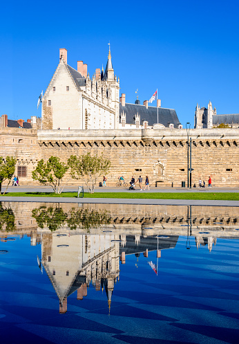 Nantes, France - September 18, 2022: The Grand Logis building of the Château des ducs de Bretagne (Castle of the Dukes of Brittany) reflecting in the reflection pool in the Elisa Mercoeur park.