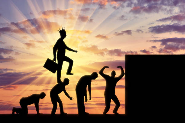 Conceptual scene of a narcissistic and selfish businessman A selfish man with a crown on his head, walking on the heads of people as on the steps to the top. Conceptual scene of a narcissistic and selfish businessman egocentric stock pictures, royalty-free photos & images