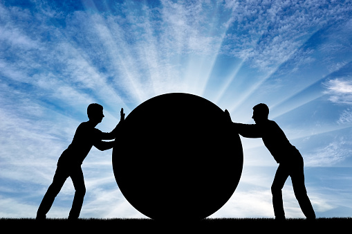 Two selfish men push the big ball, each in its own way, not yielding to each other. Conceptual scene of selfish people