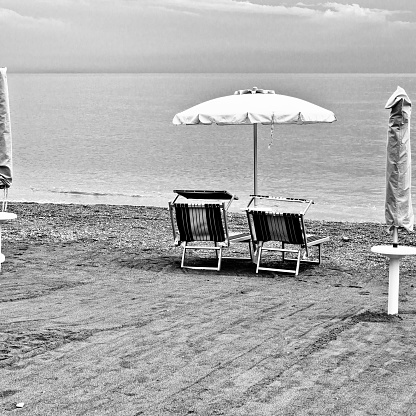 Close-up of young couple emracing on the beach. Beautiful content woman looking at camera. Black and white image.