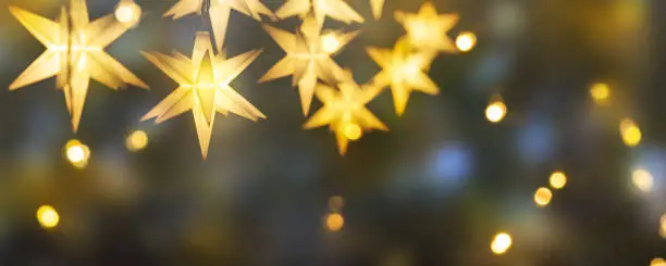 Photo of shiny christmas stars decoration on abstract background with blurred lights, illumination for celebration concept with copy space