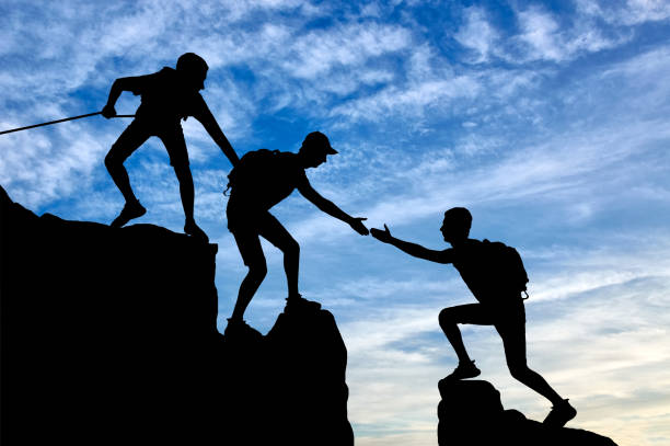 istock Silhouette of two climbers in the mountains help another climber 1433126383