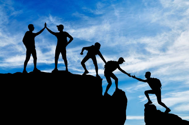Silhouette of five climbers who overcome the drudgery of working in a team Silhouette of five climbers who overcome the drudgery of working in a team. Conceptual scene of alpinists and teamwork group mountain silhouette stock pictures, royalty-free photos & images