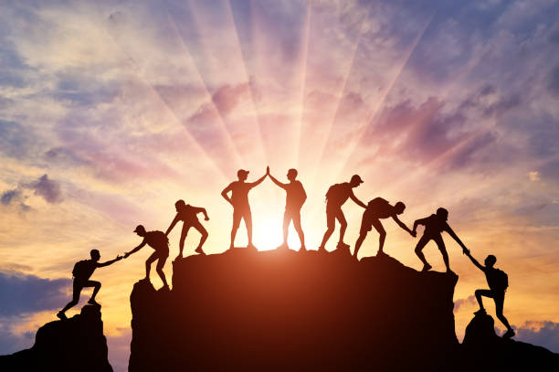 Silhouette of climbers who climbed to the top of the mountain thanks to mutual assistance and teamwork Silhouette of climbers who climbed to the top of the mountain thanks to mutual assistance and teamwork. Conceptual scene of a team of alpinists strength stock pictures, royalty-free photos & images