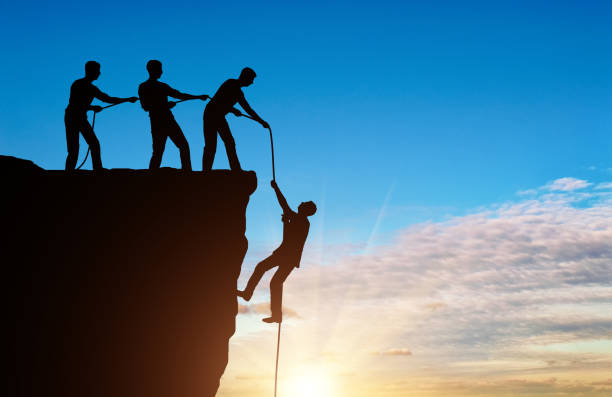 istock Silhouette of a man climbers pulling out of a cliff of another climber 1433126439