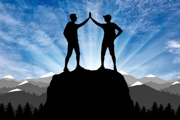Silhouette of two happy climber conquered the top. Conceptual Scene