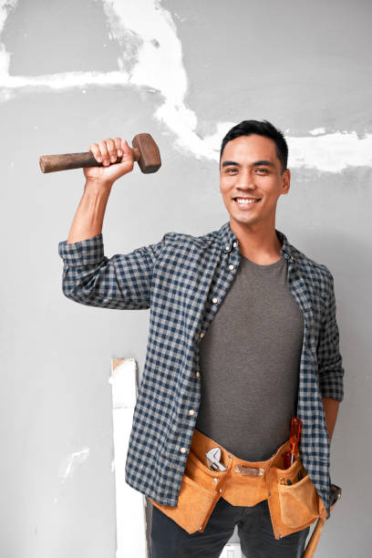 istock A young attractive Asian man holds up a mallet with strong arm doing home DIY 1433127474