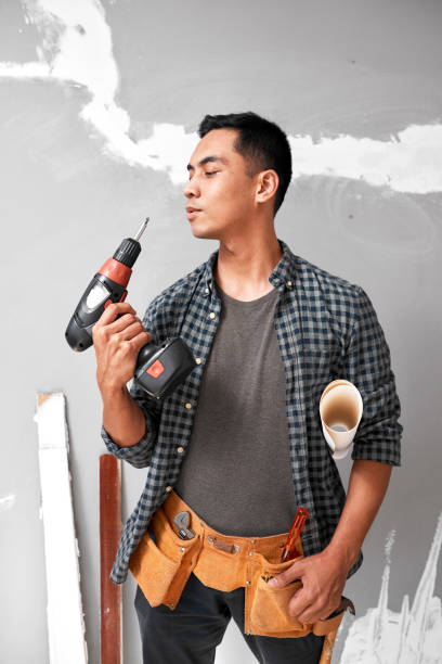 istock An attractive Asian man blows drill standing with DIY tools and toolbelt 1433127476