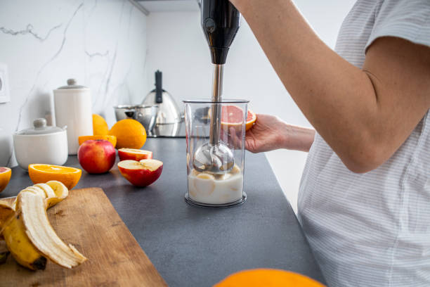 istock Woman using hand blender to mix fresh fruit smoothie in kitchen 1433130558