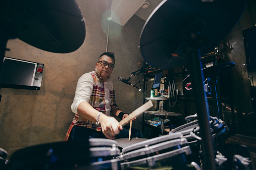 Male rock musician practicing with drums at studio