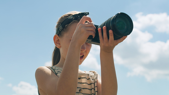 Young photographer shooting landscape. Girl taking pictures of nature, watching result, upgrading photography skills, spending leisure time outdoor. Close-up view.