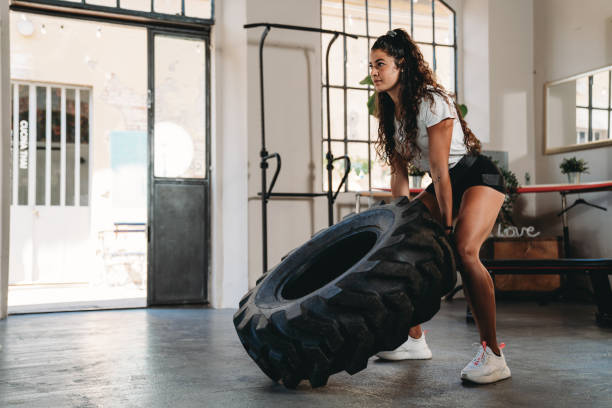 Young woman exercising with a tire in a gym stock photo