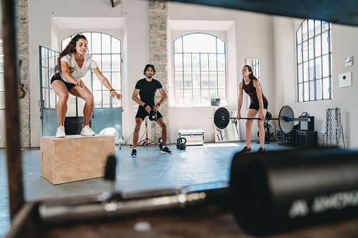 People doing cross training in an health club. Industrial loft. They are doing a cross circuit.