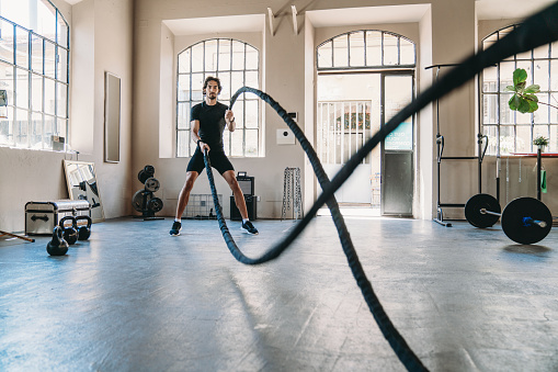 A man is training at the health club with a rope. Cross training exercising.