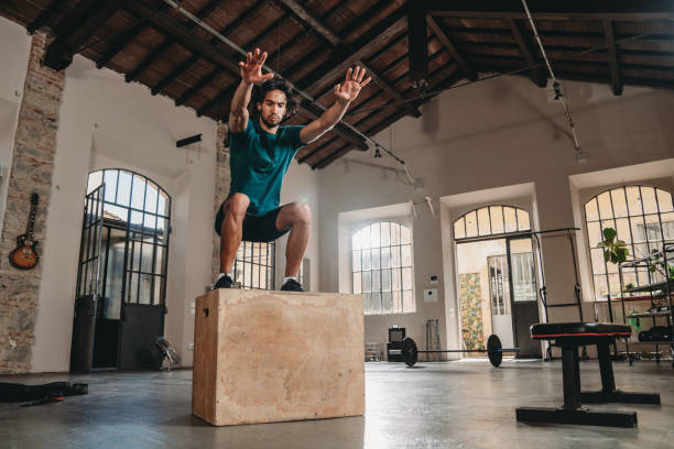 A man is doing an HIIT training at the gym jumping on a box
