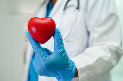 Asian woman doctor holding red heart for health in hospital.