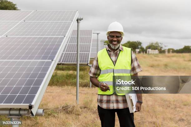 Male Engineer Stands By Solar Panels In Field Stock Photo - Download Image Now - Maintenance Engineer, Hardhat, Men