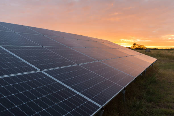 le réseau de panneaux solaires reflète le soleil levant - solar grid photos et images de collection