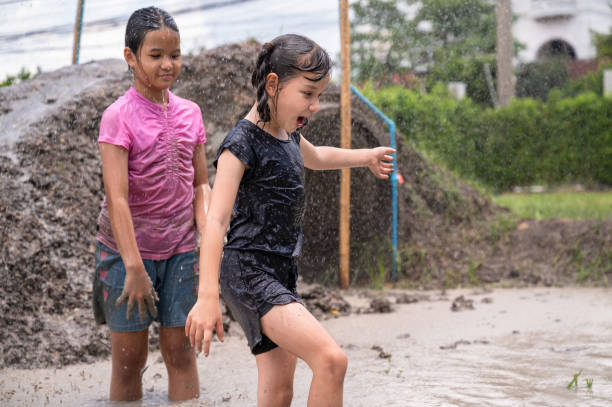 istock Funny kids girl playing in mud puddle with rain 1433143656