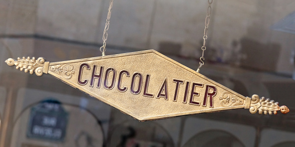 Vintage, French Art Nouveau, metal sign for an artisan French Chocolatier (Chocolate Maker) hanging in a window. in France.