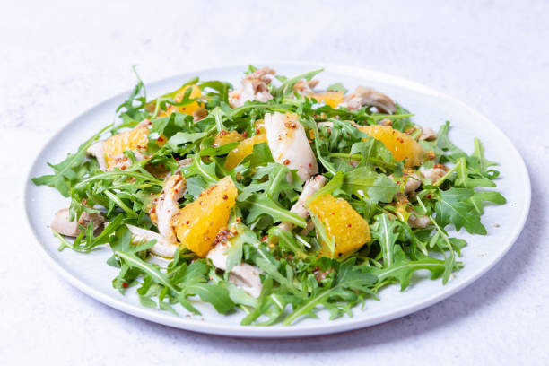 Salad with chicken, oranges and arugula. Dressing with olive oil and grain mustard. Close-up, selective focus, white background Salad with chicken, oranges and arugula. Dressing with olive oil and grain mustard. Close-up, selective focus, white background. side salad stock pictures, royalty-free photos & images