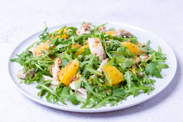 salad with chicken, oranges and arugula. dressing with olive oil and grain mustard. close-up, selective focus, white background - side salad imagens e fotografias de stock
